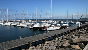 A marina with multiple boats docked, a wooden pier, and rocky shoreline. - Ferienwohnung Gerda in Ostseenahe (Wittenbeck)