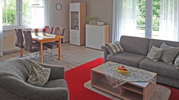 A modern living room with a dining area, a sofa, and a coffee table with fruit. - Ferienwohnung in der Nahe des Skigebietes (Willingen)