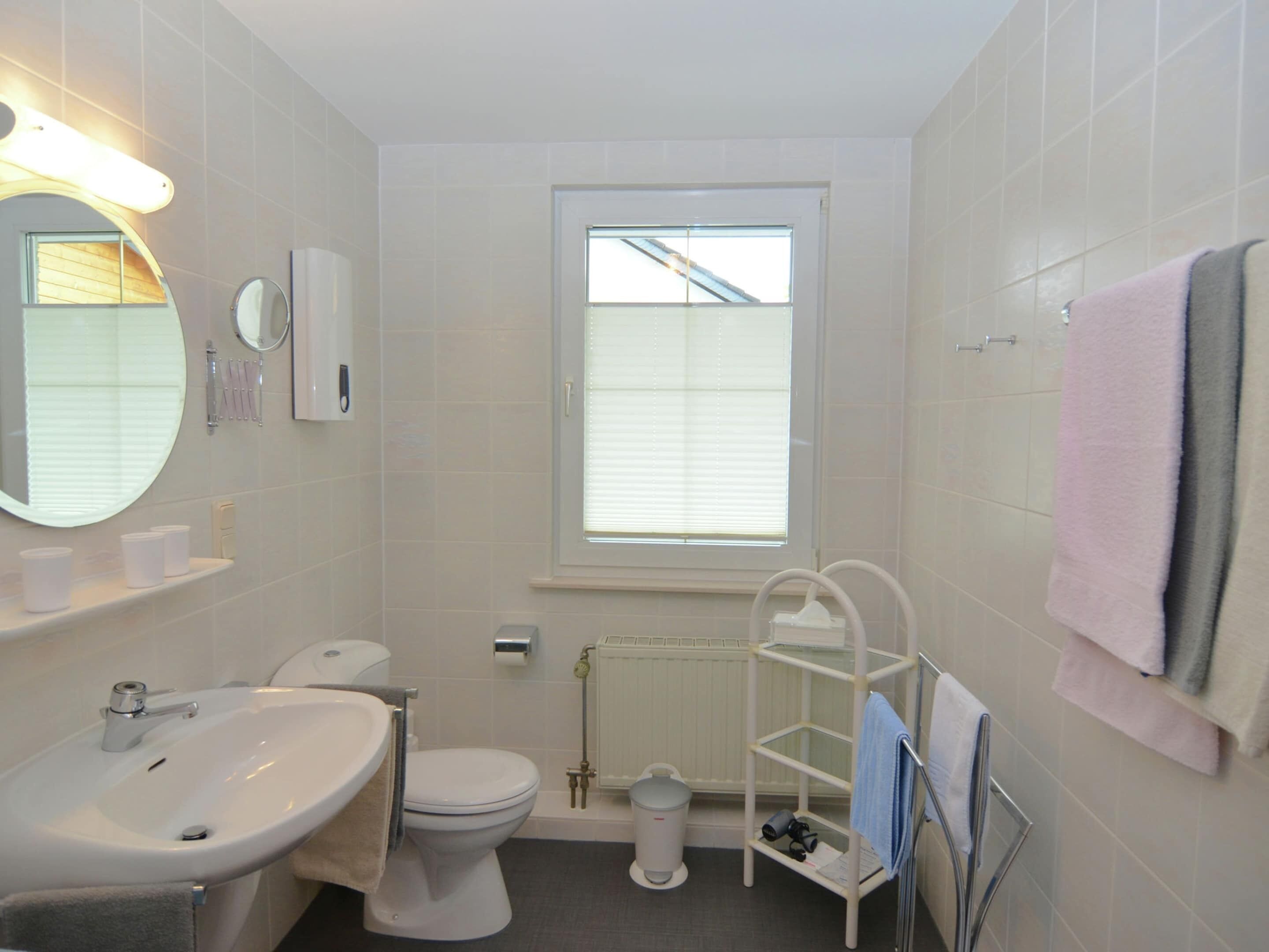 Une salle de bain avec un lavabo, des toilettes et une fenêtre.