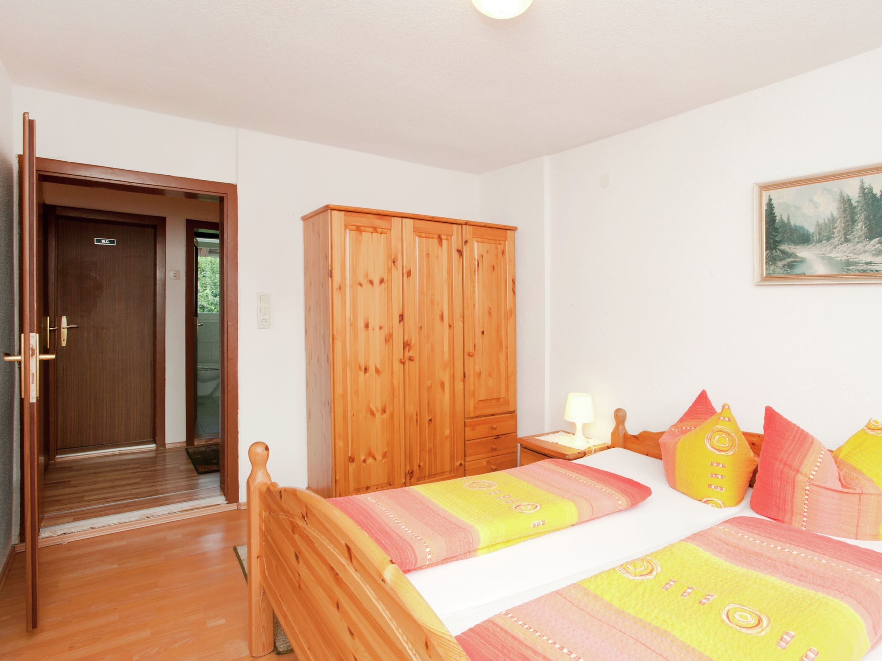 Un dormitorio con una cama de madera, un armario y un cuadro en la pared.