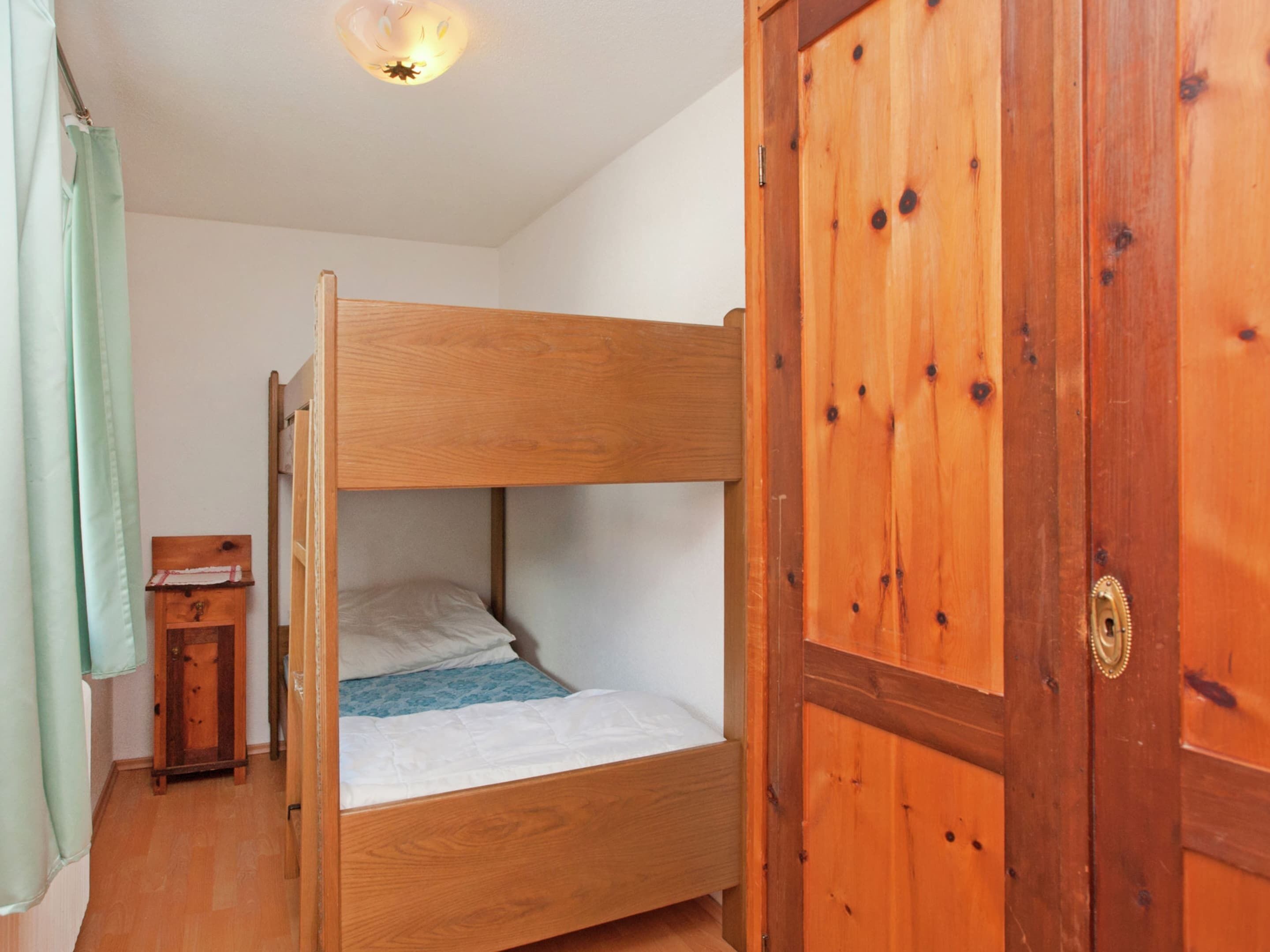 A bunk bed room with a wooden door and a small wooden cabinet.