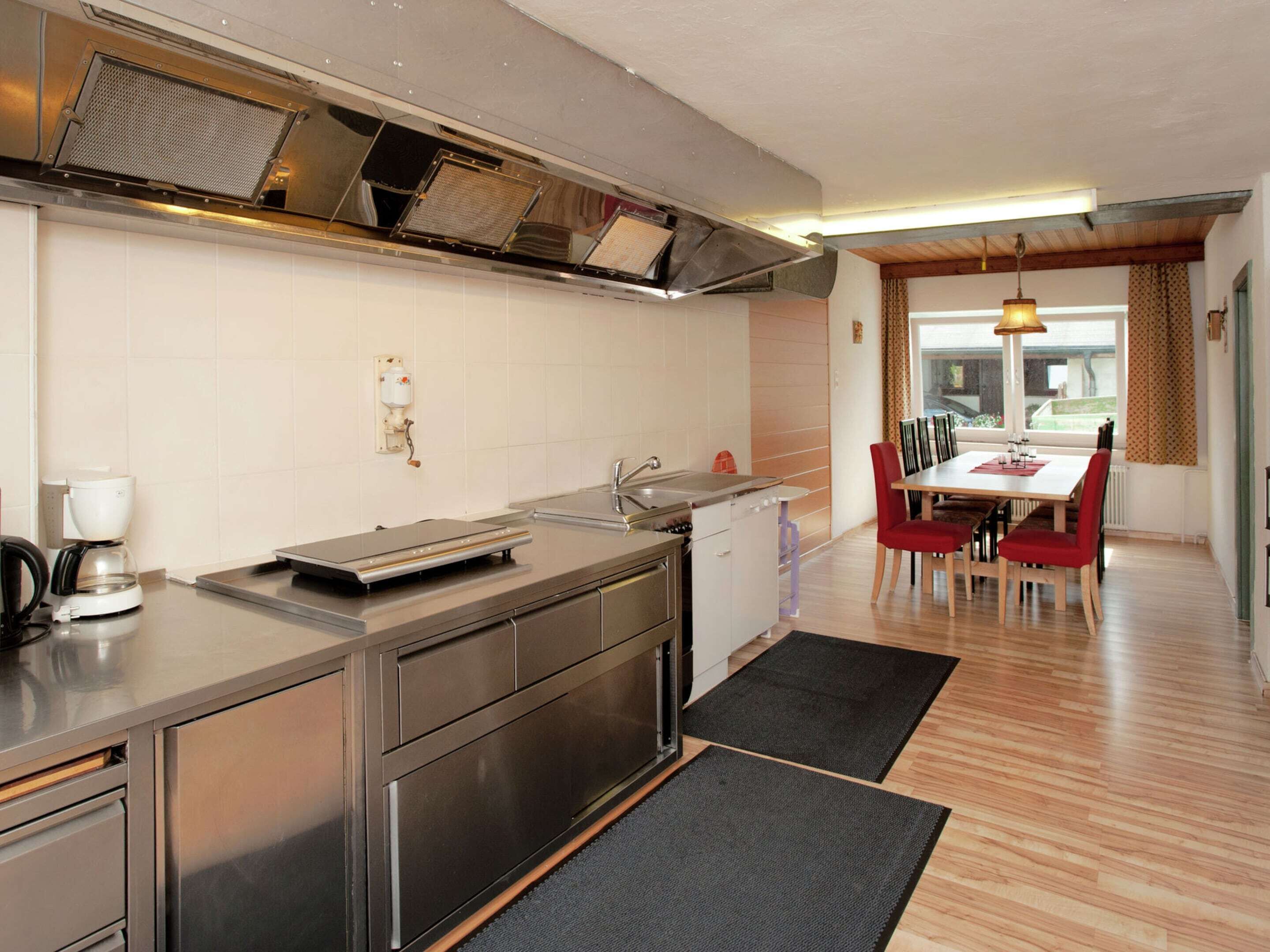A modern kitchen with stainless steel appliances, a coffee maker, and a dining area with a table and chairs.