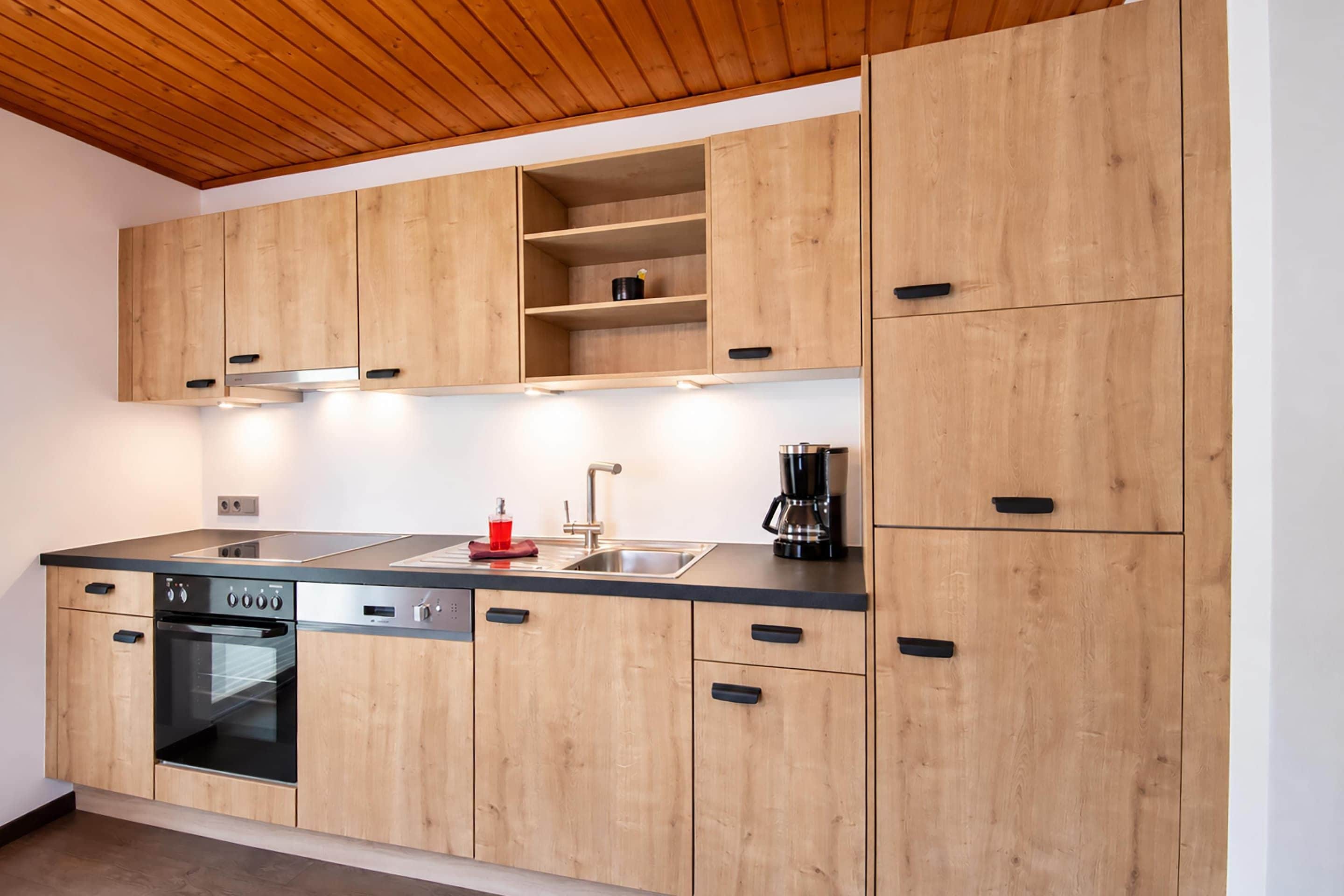 Eine moderne Küche mit Holzausstattung, einem Edelstahlspülbecken und einem eingebauten Backofen.