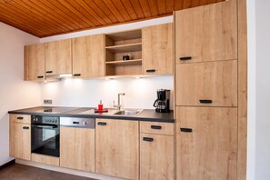 A modern kitchen with wooden cabinets, a stainless steel sink, and a built-in oven. - Cozy Apartment in Kitzbuhel near Ski Area (Kitzbuhel)