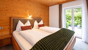 Une chambre aux murs lambrissés, avec un lit, des oreillers et une fenêtre donnant sur un paysage verdoyant.