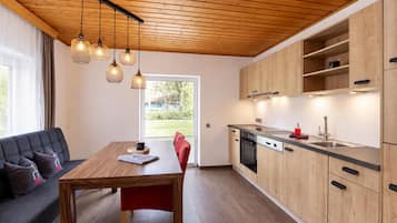 Een moderne keuken met houten kastjes, een eettafel en hanglampen.