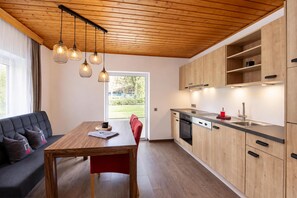 Une cuisine moderne avec des meubles en bois, une table à manger et des luminaires suspendus.