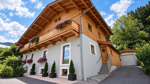Un chalet en bois à deux étages, doté d’un balcon, de plantes en pot et surplombant un ciel dégagé.