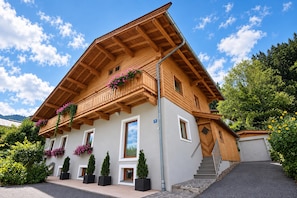 Un chalet en bois à deux étages, doté d’un balcon, de plantes en pot et surplombant un ciel dégagé.