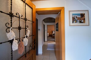 Un couloir avec une porte en bois, un objet décoratif fixé au mur et un tableau encadré.