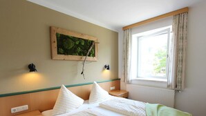 Ein Hotelzimmer mit einem Bett, zwei Nachttischen, einem Fenster mit Vorhängen, einem Wandbild und zwei Wandleuchten.