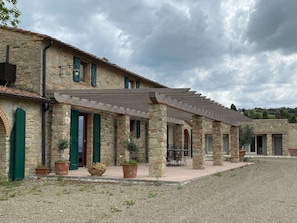 A stone building with a covered patio area, featuring outdoor seating and potted plants.