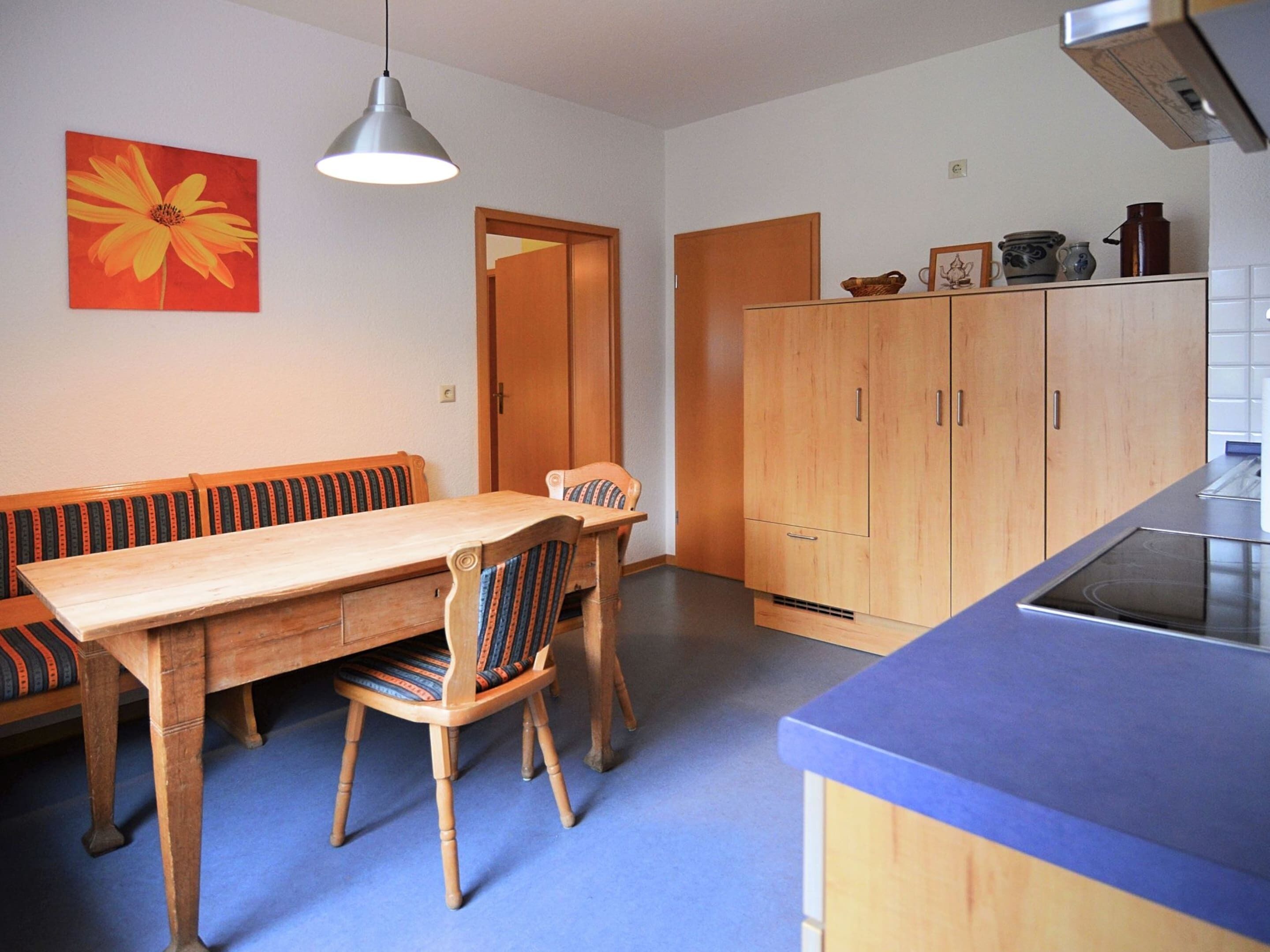 Ein Essbereich mit Holztisch und -stühlen, einer Bank, einer Hängeleuchte und Holzschränken.