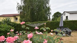 Een tuin met roze rozen, een metalen wasrek en zitplaatsen buiten.