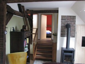 Cozy retreat with a high ceiling, wooden beams, and a warm wood-burning stove.