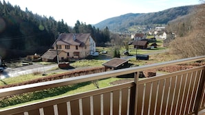 A residential area with houses, a road, and a forested hillside in the background. - Holiday Home in Vosges With Garden and BBQ (Haut-du-Them-Château-Lambert)