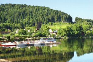 Ein See mit vertäuten Booten, umgeben von Häusern und dichtem Wald.