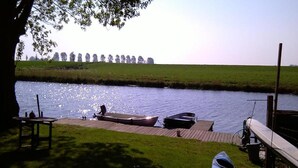 A riverside dock with boats, a table, and a bench. - Holiday Home Zoutkamp Near Lauwersmeer (Zoutkamp)