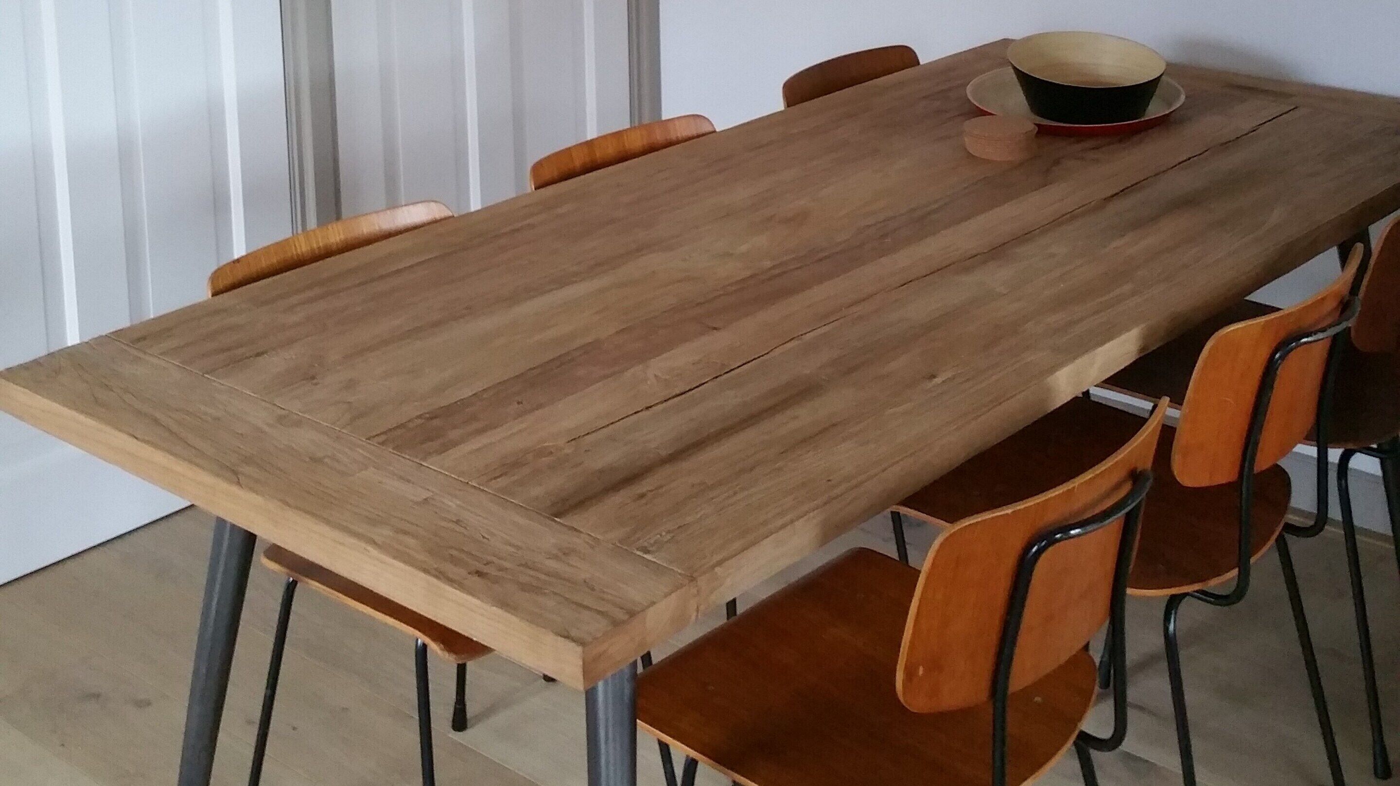 A wooden dining table with six chairs, a hat, and a bowl on it.