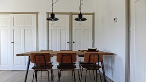 A dining area with a wooden table and six chairs, two pendant lights, and white double doors. - Holiday Home Zoutkamp Near Lauwersmeer (Zoutkamp)