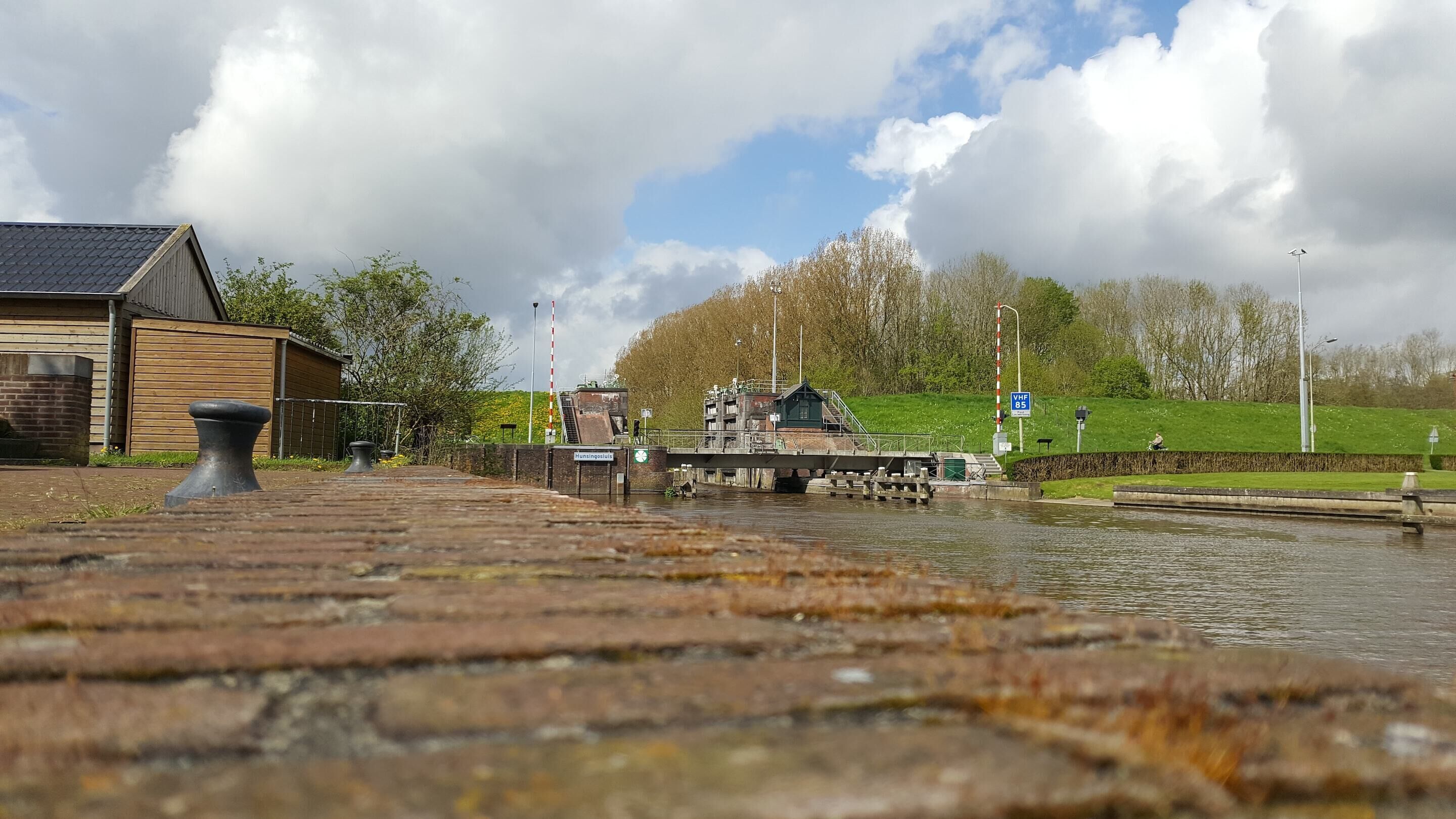 A lock gate with a wooden building and a grassy area in the background.