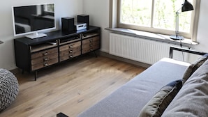 A bedroom with a bed, a TV, a dresser, and a window with a view. - Holiday Home Zoutkamp Near Lauwersmeer (Zoutkamp)