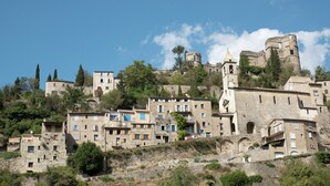 A historic village with stone buildings, a prominent tower, and a castle on a hill. - Apartment in Rhone Alpes Near Ski Slopes (Montbrun-les-Bains)