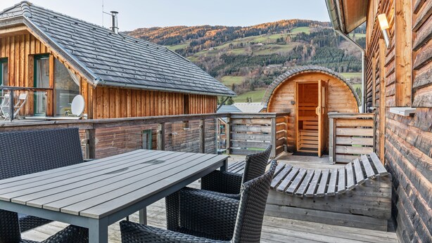 A wooden cabin with a balcony, a dining table, and wicker chairs. - Spacious Holiday Home in Styria near Kreischberg Ski Area (Sankt Georgen am Kreischberg)