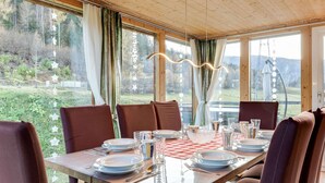 A dining area with a table set for four, large windows, and a view of a forested area. - Spacious Holiday Home in Styria near Kreischberg Ski Area (Sankt Georgen am Kreischberg)