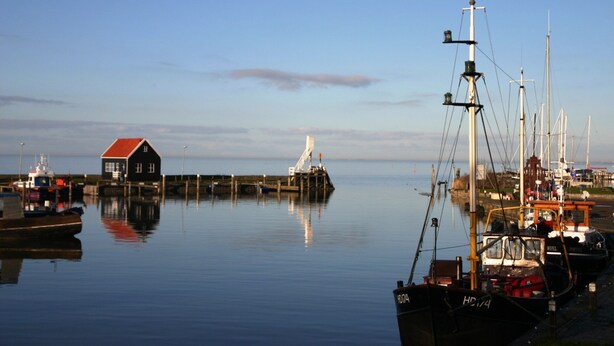 A harbor with boats, a lighthouse, and a small building with a red roof. - Holiday Home in Hindeloopen by Lake (Hindeloopen)