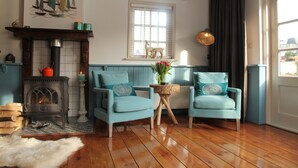 A cozy room with a fireplace, two armchairs, a small table, and a window with a view. - Holiday Home in Hindeloopen by Lake (Hindeloopen)