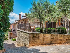 A stone building with a staircase leading to a wooden deck, surrounded by greenery and a stone wall. - Spacious Holiday Home in Ca' De' Grimaldi near Town Center (Castellarano)