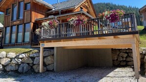 Una baita di legno con balcone, fondamenta in pietra e vista sul paesaggio circostante.