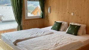 Una stanza con rivestimento in legno e un letto con due cuscini, uno verde e uno bianco.