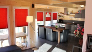 Una cucina moderna con isola centrale, una zona pranzo con tavolo e sedie, e un angolo salotto accogliente con divano.