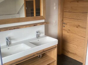 A bathroom with two sinks, a wooden vanity, and a mirror with a wooden frame. - Chalet in Hohentauern / Styria With Sauna (Hohentauern)