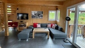 Un interno in legno con un divano componibile, una televisione e un'area pranzo.