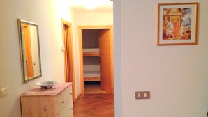 Um corredor com uma cômoda de madeira, um espelho e um quadro na parede.