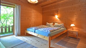 A wooden cabin bedroom with a bed, bedside lamps, and a window with a view of greenery. - Vintage Holiday Home in Grafenried With Garden (Drachselsried)
