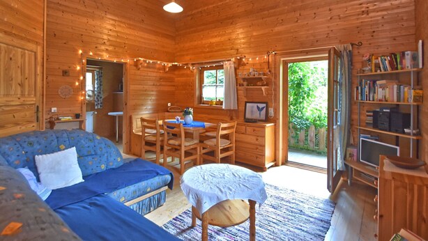 A cozy cabin interior with a wooden interior, a sofa, a dining table, and a bookshelf. - Vintage Holiday Home in Grafenried With Garden (Drachselsried)