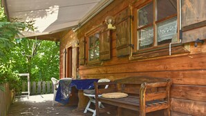A wooden cabin with a porch, a bench, and a table covered with a blue cloth. - Vintage Holiday Home in Grafenried With Garden (Drachselsried)