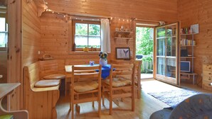 A wooden cabin interior with a dining area, a bookshelf, and a television. - Vintage Holiday Home in Grafenried With Garden (Drachselsried)