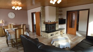 A living room with a fireplace, a sofa, a dining table, and a TV. - Holiday Home in Stavelot Near Tennis Court (Stavelot)