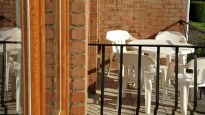 A patio area with a brick wall and white plastic furniture. - Holiday Home in Stavelot Near Tennis Court (Stavelot)