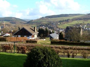 A rural landscape with a house in the foreground, a small village in the background, and rolling hills. - Holiday Home in Stavelot Near Tennis Court (Stavelot)