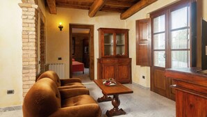 A cozy living room with a sofa, wooden cabinet, and a television. - Farmhouse in Aulla With Private Pool (Aulla)
