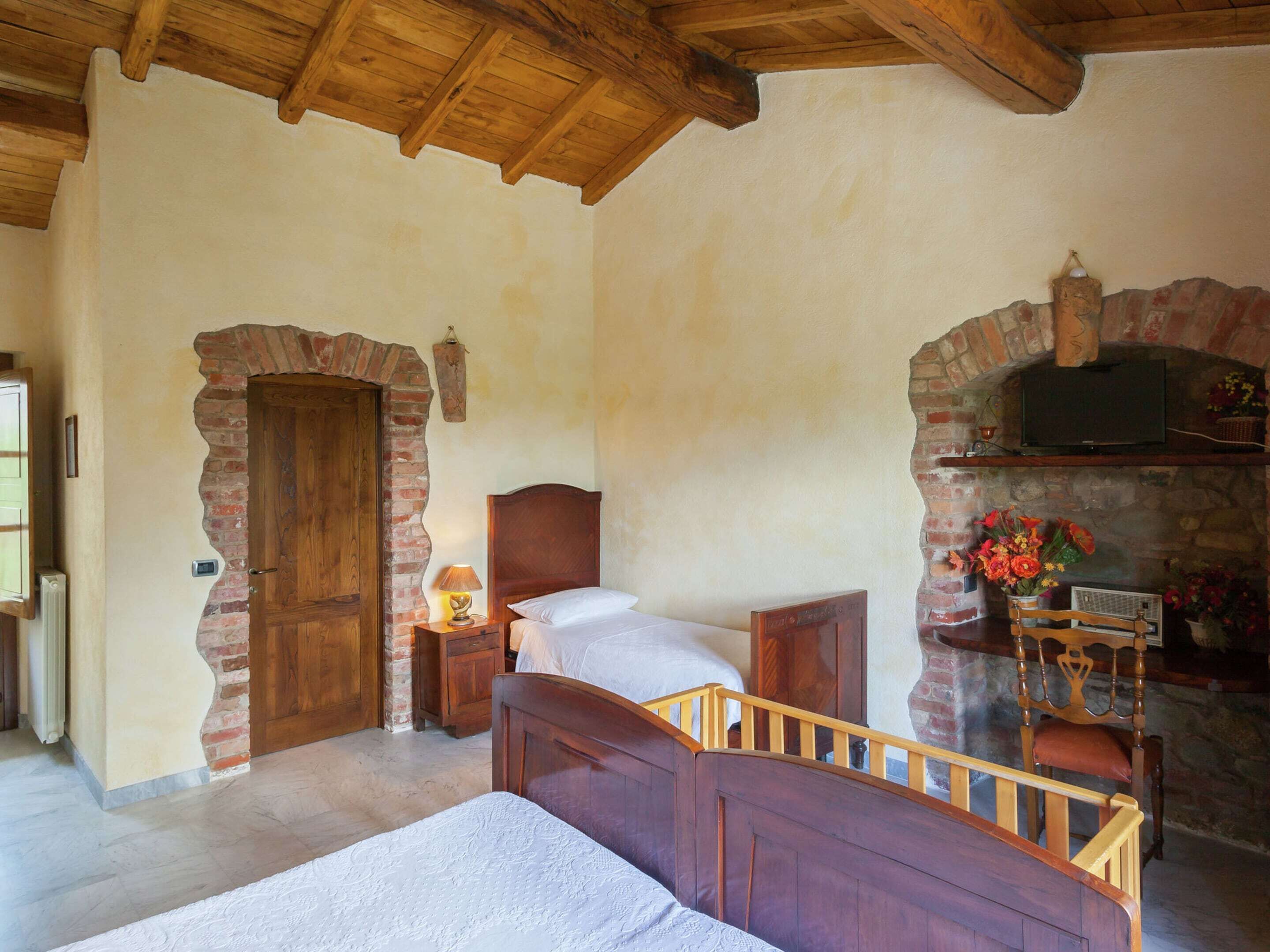 A rustic bedroom with a wooden bed, a brick fireplace, and a stone wall.