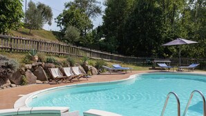 A swimming pool with a wooden deck, lounge chairs, and a wooden fence. - Farmhouse in Aulla With Private Pool (Aulla)