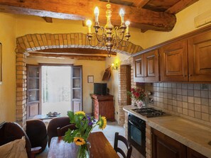 A rustic kitchen with exposed brick walls, wooden cabinets, a stone archway, and a chandelier. - Farmhouse in Aulla With Private Pool (Aulla)