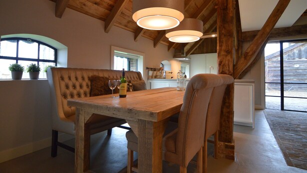 A dining area with a wooden table, cushioned bench, and pendant lighting.